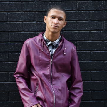 barber using styling spray on young man with black hair, short on sides and long in a quiff on top